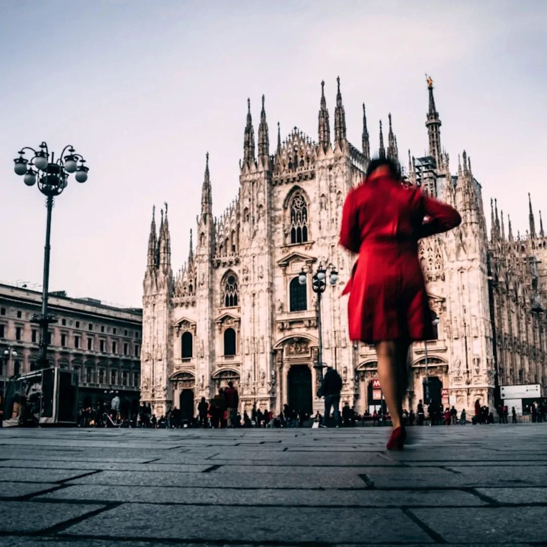 woman in red dress standing on gray concrete floor near brown concrete building during daytime